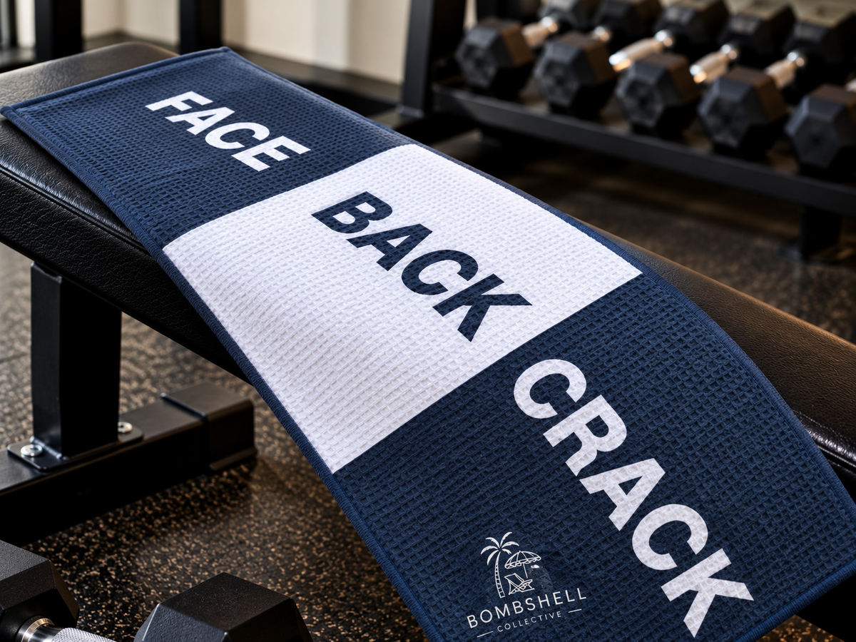 Bombshell Collective Face Back Crack gym towel in deep sea blue laid on a gym bench, featuring a bold three-section design.