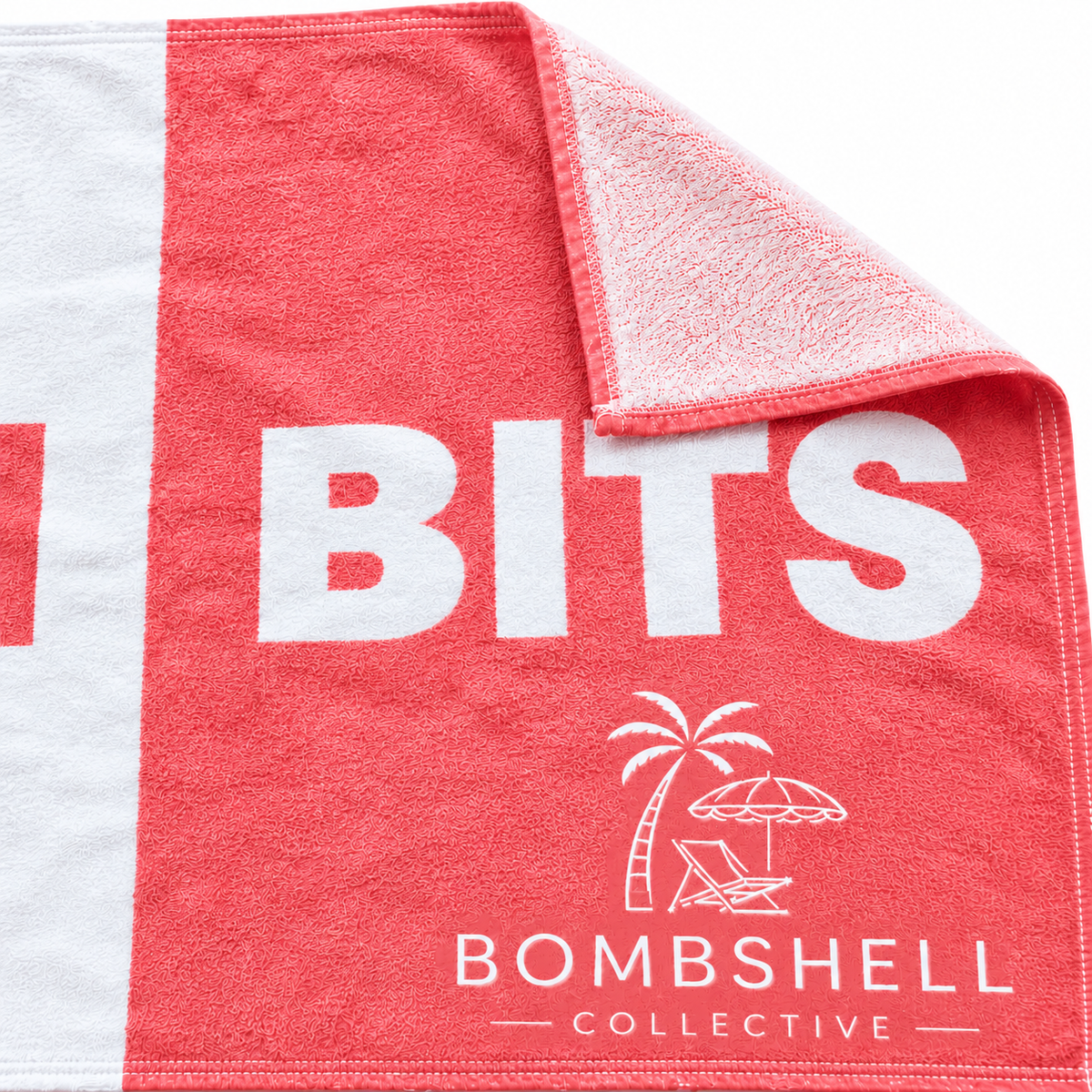 Close-up of coral Face Bum Bits bath towel showing fabric texture, white lettering and Bombshell Collective beach logo.