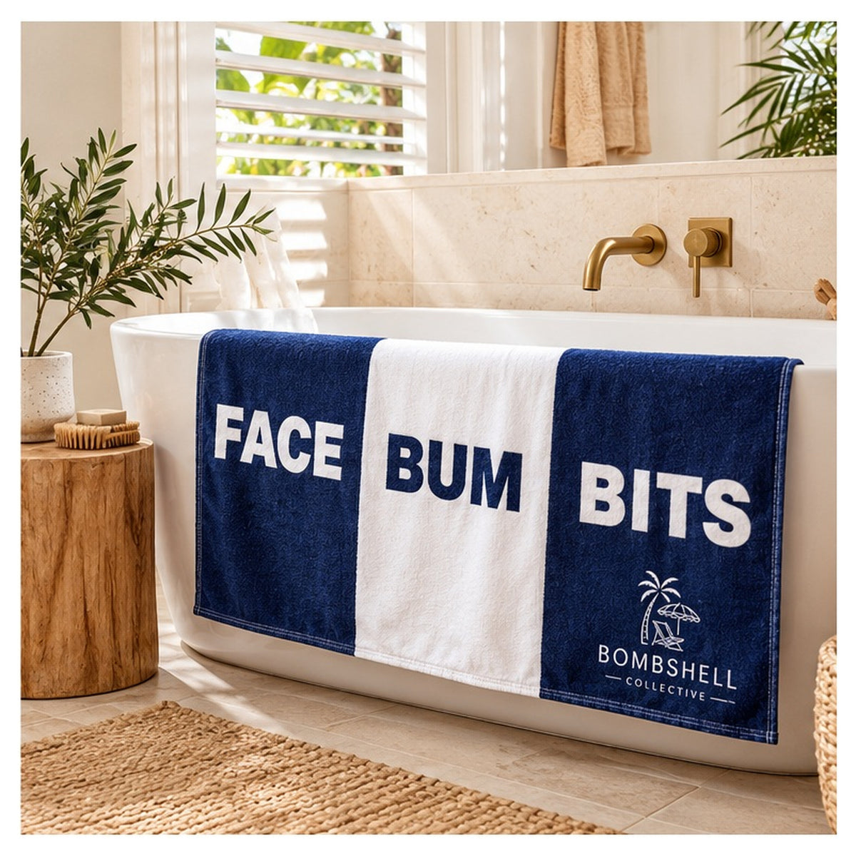 Bombshell Collective Face Bum Bits deep sea blue and white bath towel displayed in a coastal bathroom beside a freestanding bathtub