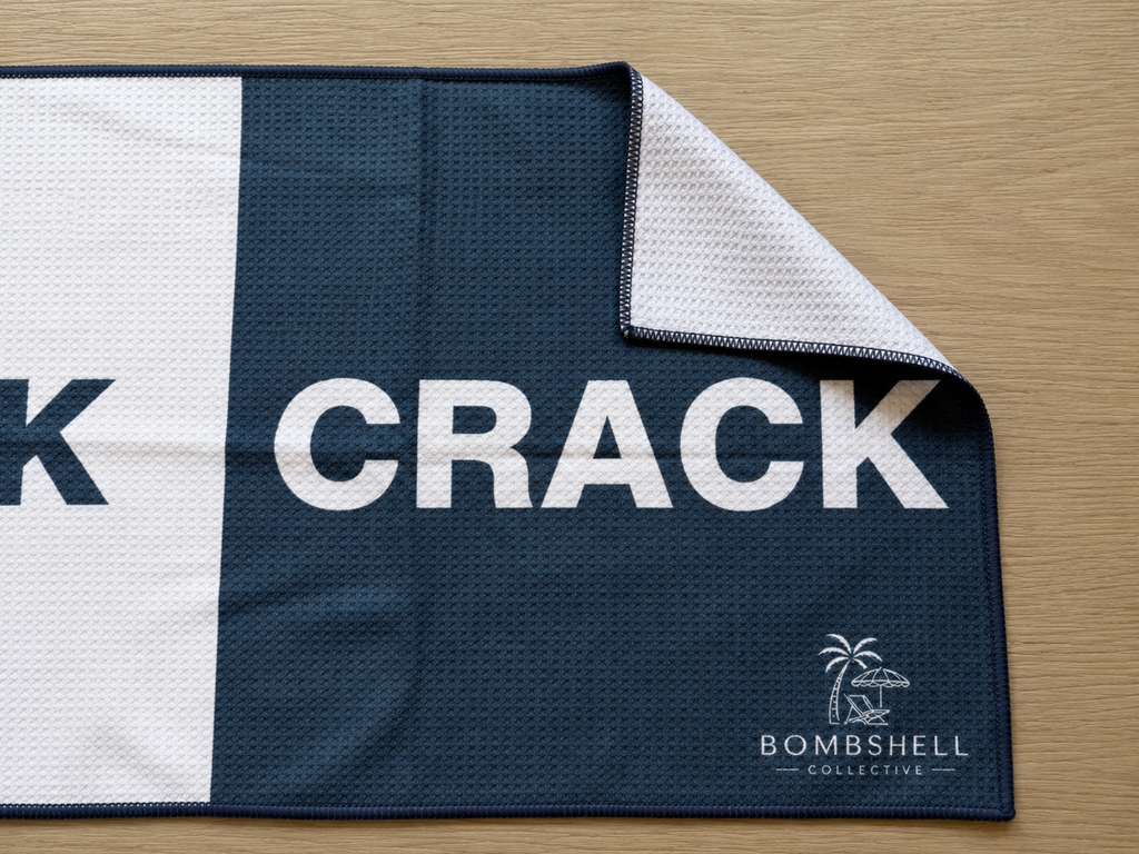 Close-up of Bombshell Collective deep sea blue waffle-textured gym towel showing the folded corner and signature logo.