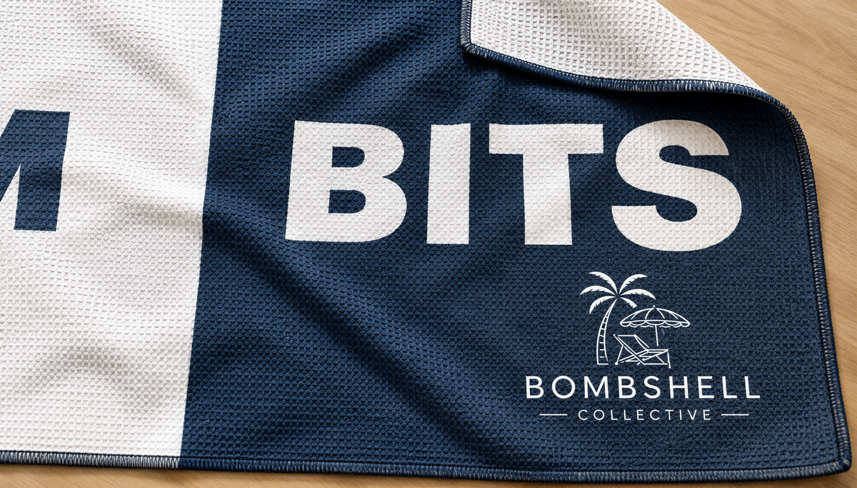Close-up of the Face Bum Bits beach towel in deep sea blue, showing textured sand-free waffle microfibre fabric, folded corner and Bombshell Collective branding.