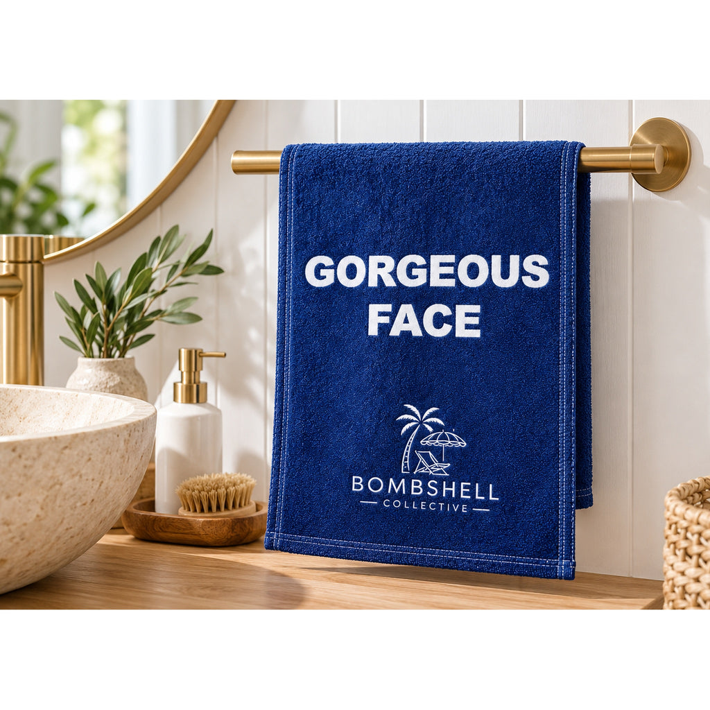 Deep sea blue novelty hand towel featuring the playful Gorgeous Face slogan by Bombshell Collective